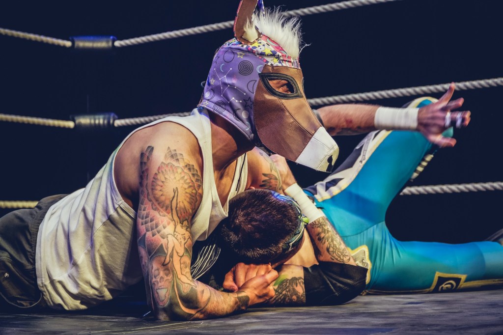 A wrestler wearing Bottom’s donkey mask grapples with another wrestler in the ring during BARDCORE: Midsummer Mayhem.