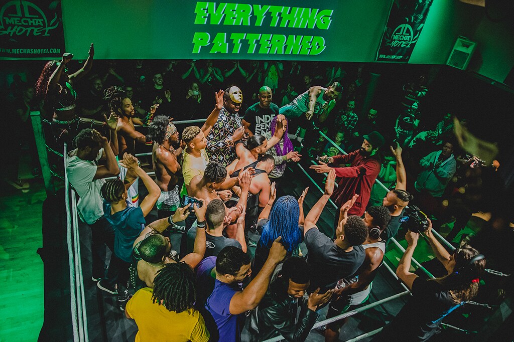 The all-Black cast of Everything Patterned gathers in and around the wrestling ring with members of the audience.